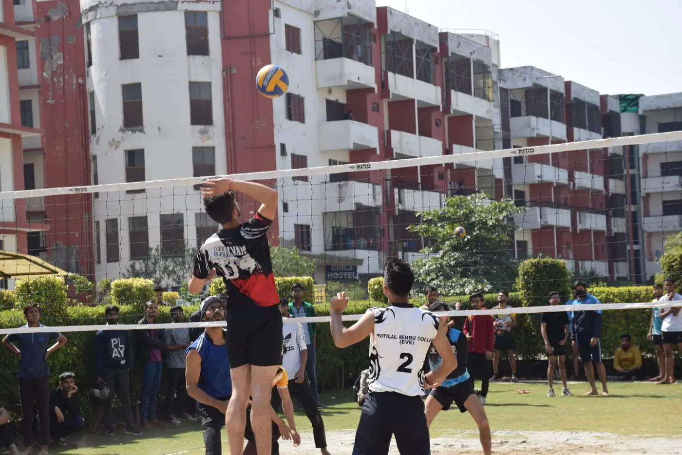 Volleyball court on campus with academic blocks behind