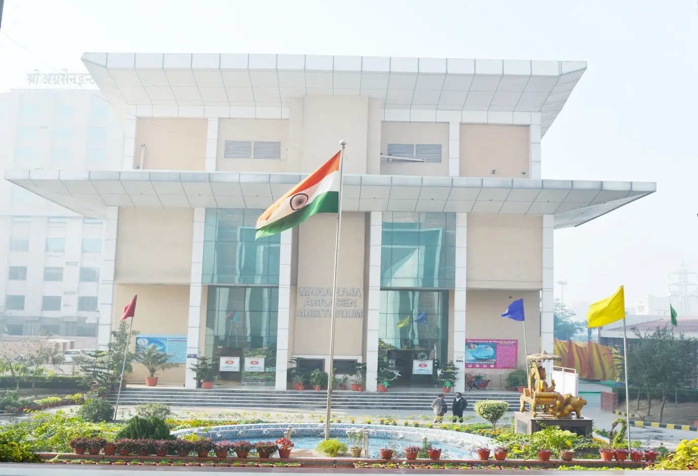 Campus building front with flagpole and fountain