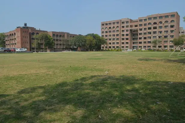 Red-brick academic blocks across the campus lawn